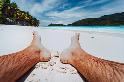 Low section of man on shore against sky