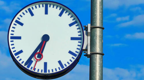 Low angle view of clock against blue sky