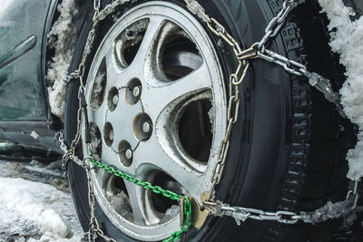 Snow chains on a car wheel. close-up. a car wheel dressed in chains. safety on winter snowy roads