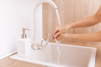 Cropped hand washing hands in bathroom