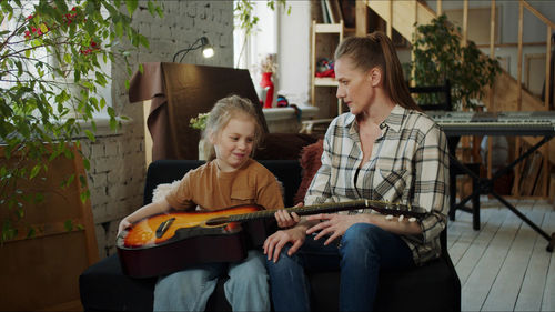 Mother teaching guitar to daughter