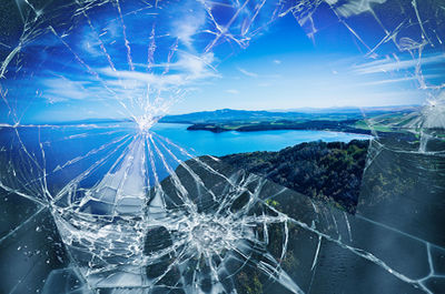 Close-up of broken glass window against blue sky