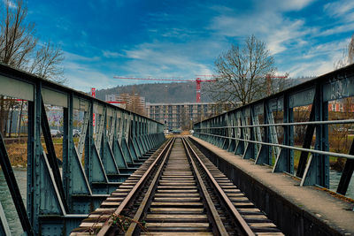 Footbridge over railroad tracks against sky