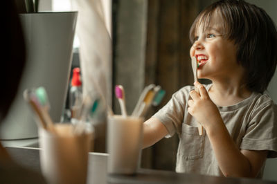 The boy brushes his teeth with a toothbrush made of ecological material