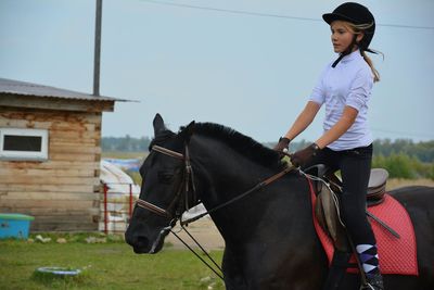 Jockey riding black horse against clear sky