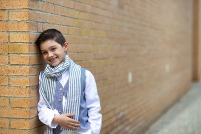 Child poses for fashion leaning on corner, sympathetic and laughing. short-haired dark-haired boy.