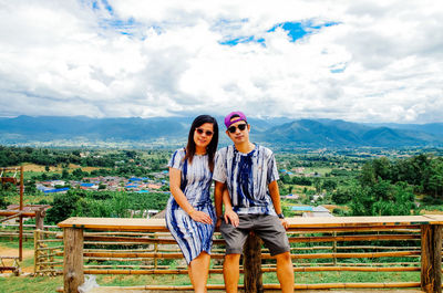 Portrait of young couple standing against railing