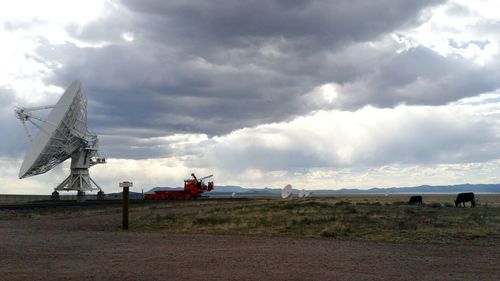 Wind turbines on field against cloudy sky