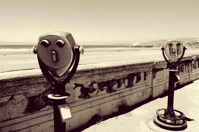 Close-up of coin-operated binoculars by sea against clear sky