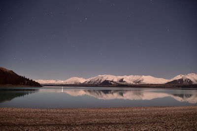 Scenic view of lake and mountains against sky at night