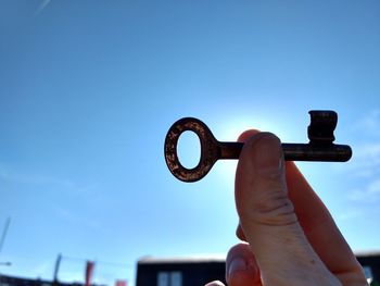 Close-up of hand holding eyeglasses against clear blue sky