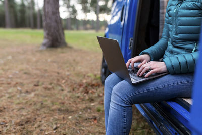 Midsection of man using mobile phone while sitting on seat