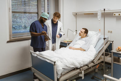 Male nurse showing digital tablet to doctor and patient in hospital