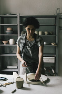 Female owner modeling clay at ceramics workshop