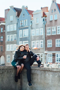 Portrait of smiling young woman against buildings in city