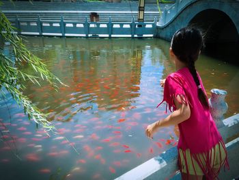 Girl feeding fishes in lake