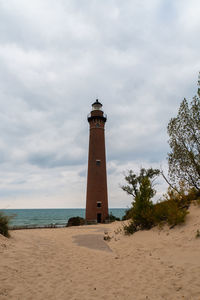 Lighthouse by sea against sky