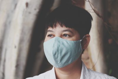 Woman wearing mask looking away while standing outdoors