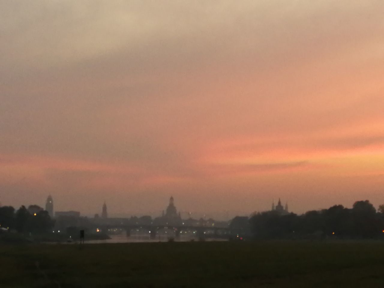 SCENIC VIEW OF ILLUMINATED BUILDINGS AGAINST ORANGE SKY