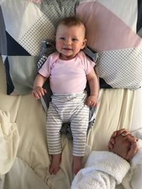 High angle portrait of cute baby girl on bed at home
