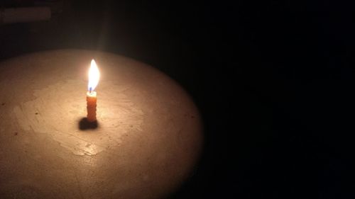 Close-up of illuminated candle in darkroom