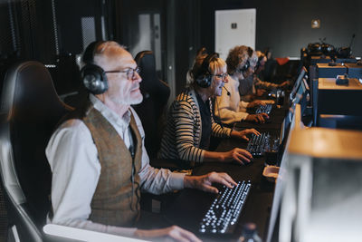 Senior male and female friends playing game on computers in gaming center