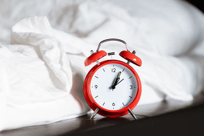 Red retro alarm clock at bed at home in hotel bedroom. morning time to wake up early rise day sleep