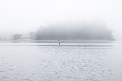 Scenic view of lake against sky during foggy weather