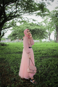 Woman standing by tree on field