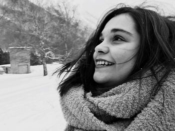 Close-up of smiling young woman wearing scarf during winter