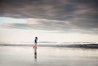 Young child walking on cold beach in new zealand