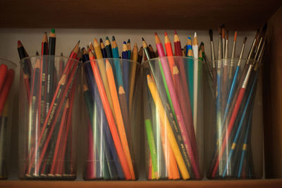 Colored pencils in plastic containers on shelf