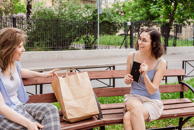 Friends are discussing a new book on the street. communication of girls with social distancing