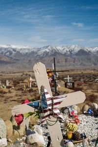 Wooden cross on grave in desert cemetery with distant snowy mountains