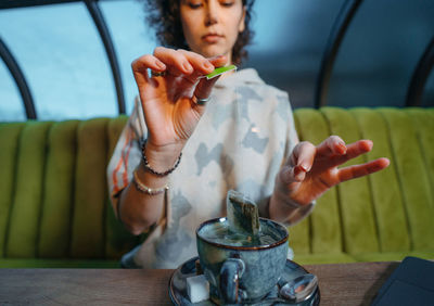 Midsection of woman holding drink while sitting on table