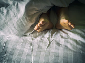 Low section of woman relaxing on bed