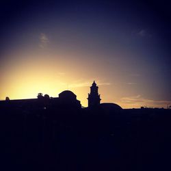 Silhouette buildings against sky at sunset