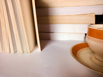 Cropped image of cup and saucer by book