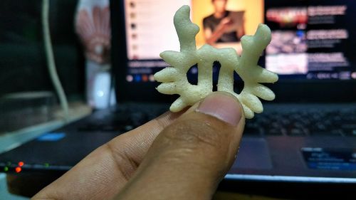 Cropped hand holding snack against laptop