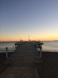 Pier on beach at sunset