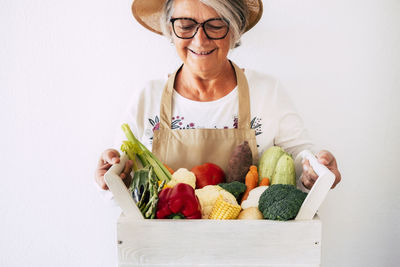 Portrait of smiling woman holding food against white background