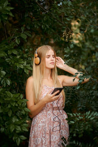 Young woman wearing hat standing against plants