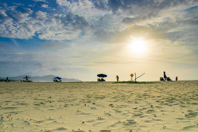 People on beach against sky during sunset