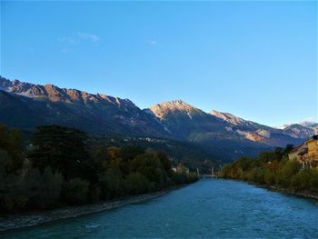 Scenic view of lake and mountains against blue sky