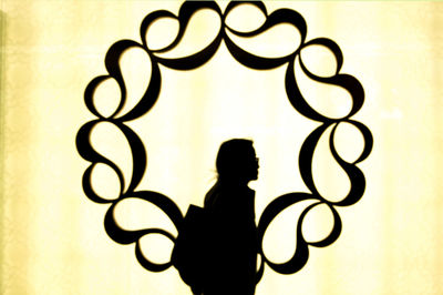 Rear view of silhouette woman standing against illuminated wall