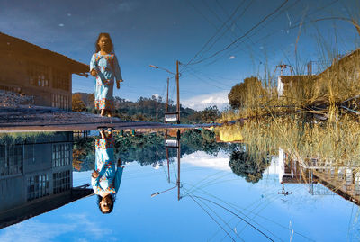 Woman standing by puddle against sky