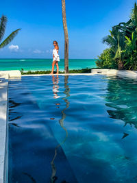 Full length of woman standing by infinity pool