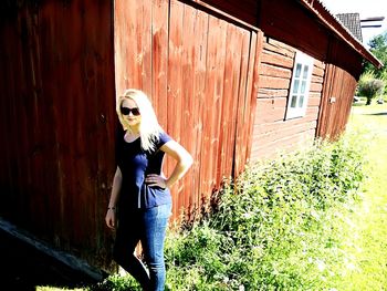 Portrait of young woman standing against wooden wall
