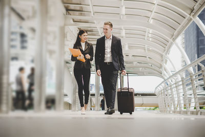 Coworkers talking while walking on footbridge in city