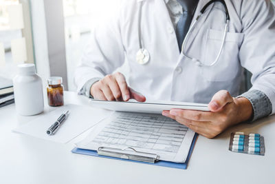 Midsection of man using mobile phone on table